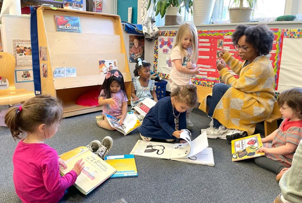 Teacher leading young children in a classroom reading activity with books