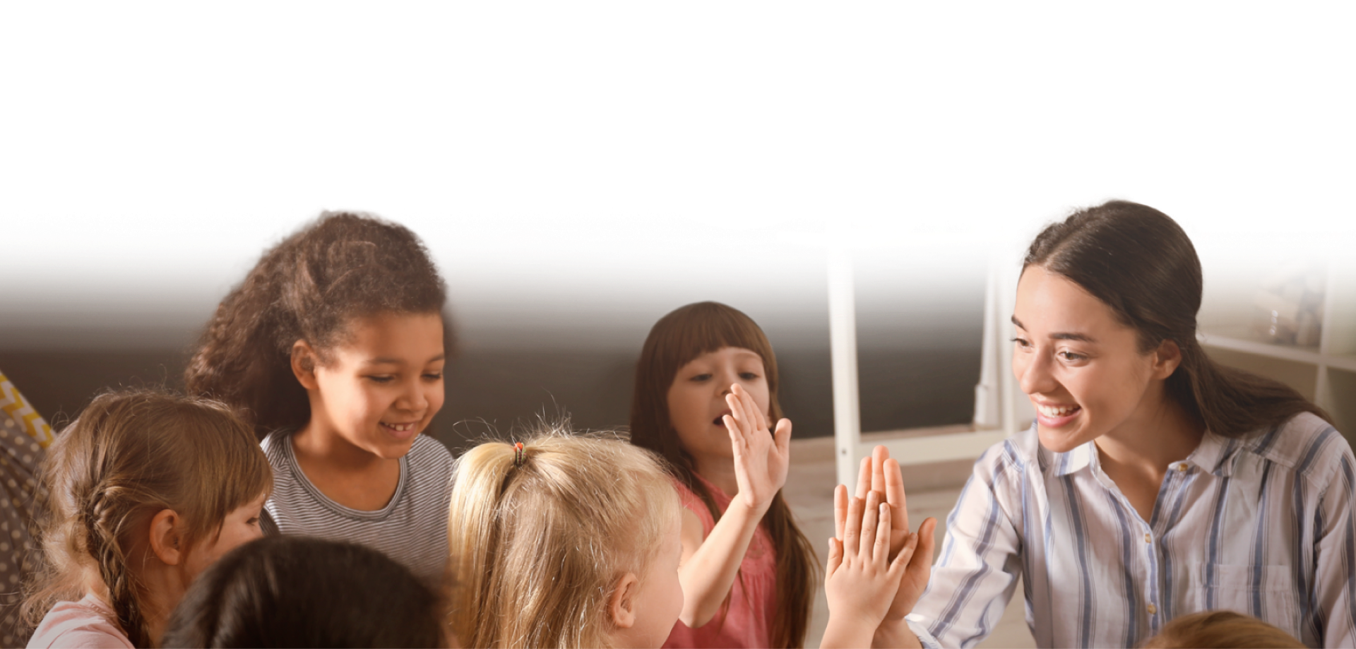 A teacher with a group of students, high-fiving one of the students.