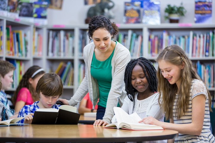 Elementary students working with teacher in library