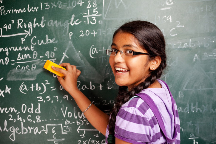 Cheerful Indian Girl Student Erasing Mathematics Problems from Greenboard